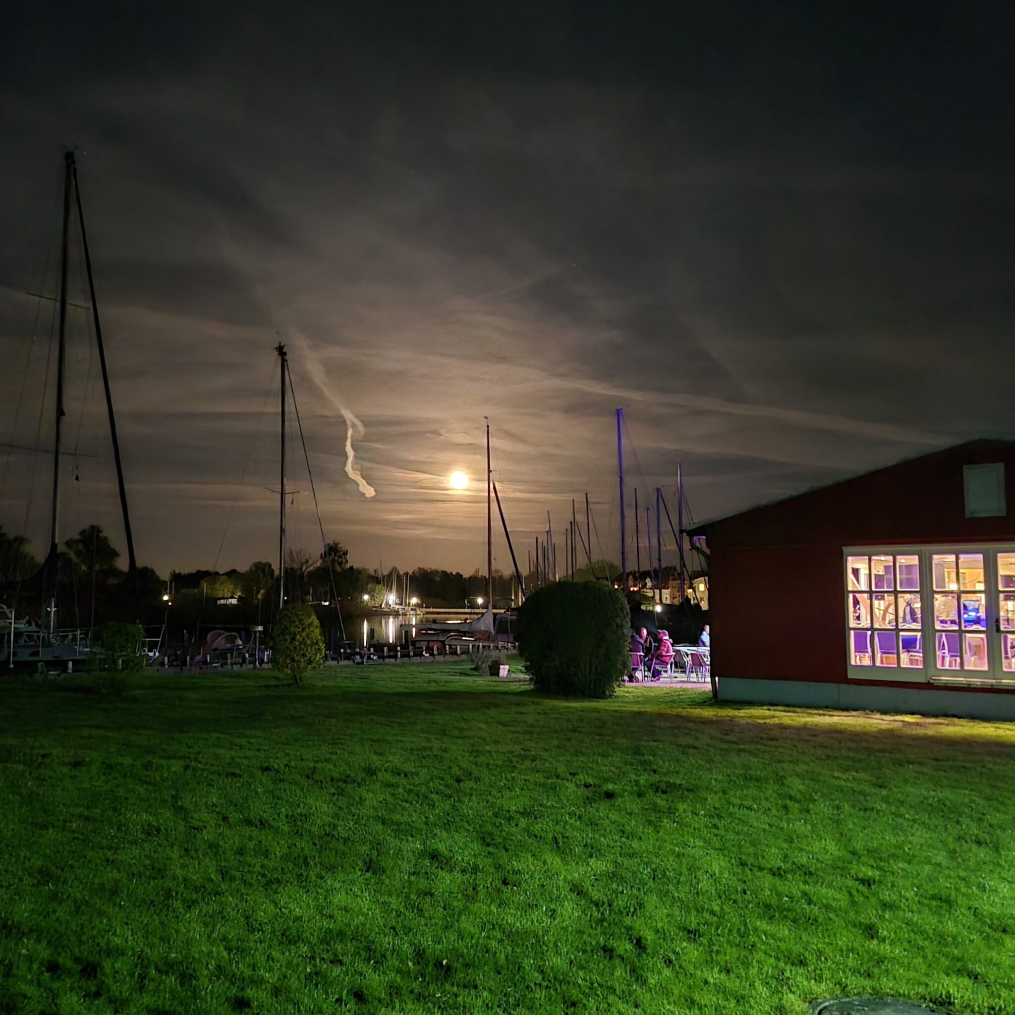 Abendstimmung mit Vollmond. Im Vereinshaus ist noch Licht.